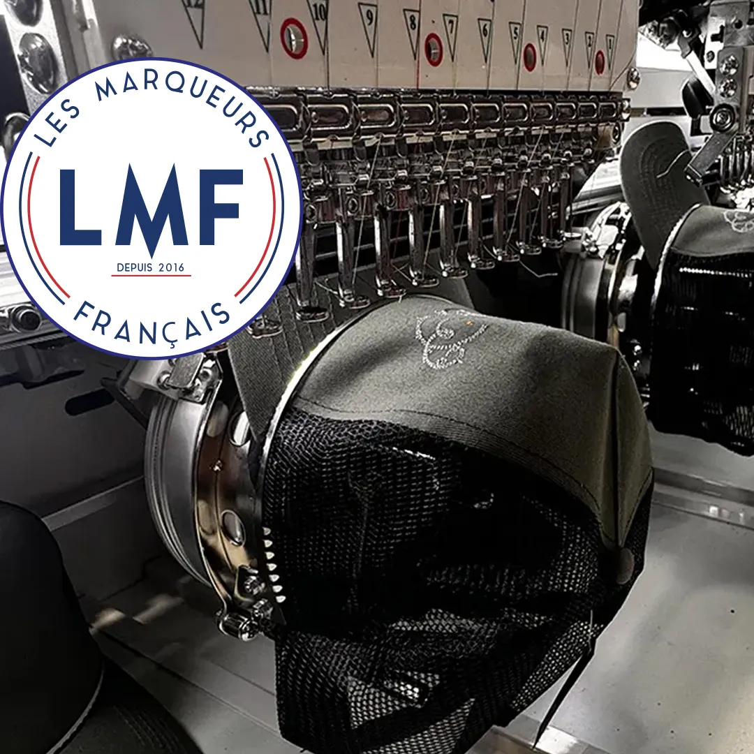 Casquette personnalisée en cours de broderie sur une machine professionnelle, illustrant le savoir-faire des Marqueurs Français en personnalisation textile.